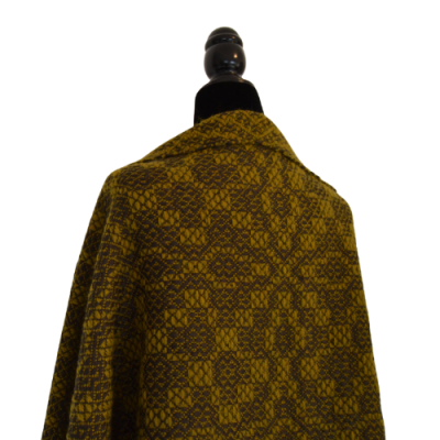 Manta ou xale geométrico amarelo mostarda e castanho num manequim preto