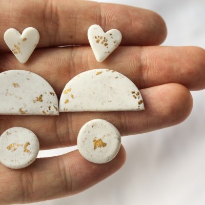 Brincos creme com manchas castanhas em vários formatos na mão