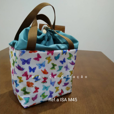 Saco de tecido com padrão de borboletas coloridas e fecho superior em tecido azul