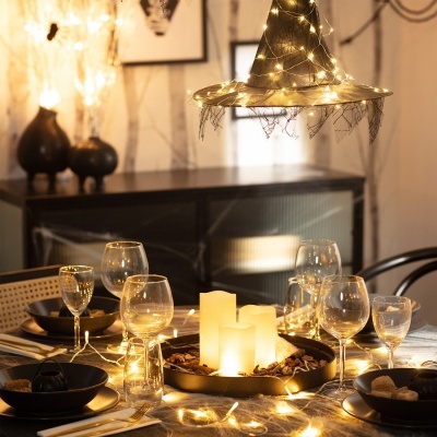 Mesa de jantar decorada com pratos pretos e velas com luzes decorativas
