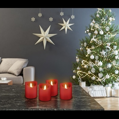 Sala de estar com decoração de Natal incluindo árvore decorada, velas vermelhas acesas na mesa e duas estrelas brancas penduradas na parede