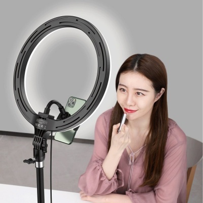 Mulher a aplicar batom sentada junto de anel de luz LED preto com smartphone