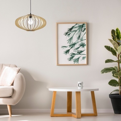 Sala com mesa branca e pernas de madeira, caneca 'C', sofá bege, quadro de folhas verdes, candeeiro de madeira e planta verde.