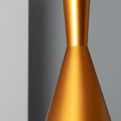 Objeto metálico dourado fosco em forma cónica contra fundo cinza