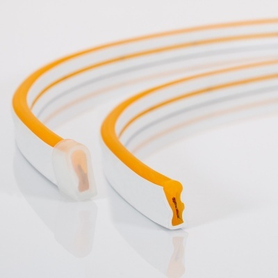 Dois perfis de vedação em silicone branco e laranja com base adesiva sobre superfície branca.