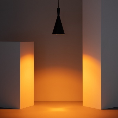 Candeeiro de teto negro em cone entre paredes brancas com luz quente