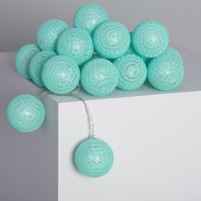 Cordão de luzes com bolas de fio azul turquesa sobre superfície branca
