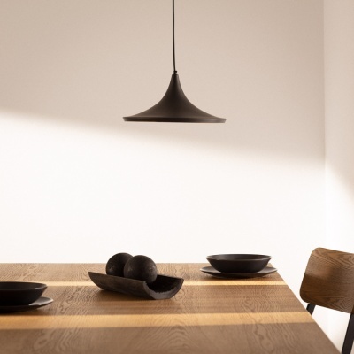 Lustre preto suspenso sobre mesa de madeira com pratos e fruteira preta