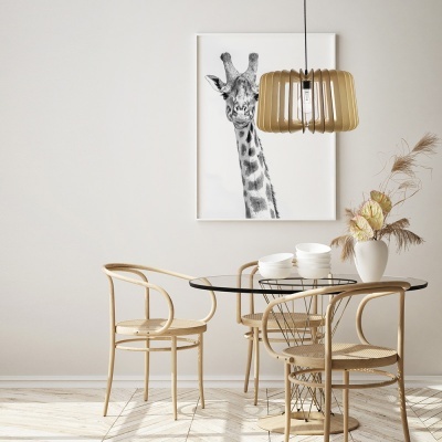 Mesa de jantar redonda com tampo de vidro, cadeiras de madeira clara, luminária pendente de madeira, vaso branco com flores secas e quadro de girafa em parede branca