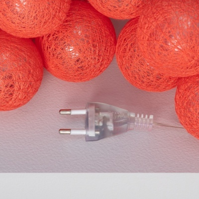 Fio de luzes com bolas de fios laranja e ficha elétrica transparente