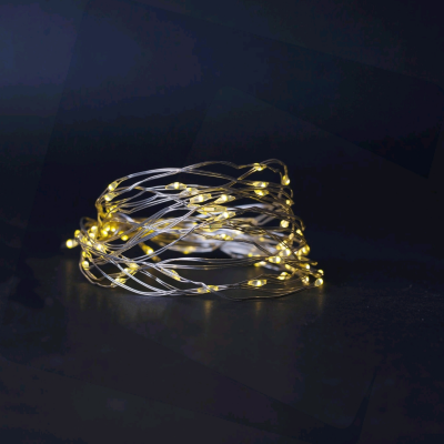 Fios de luzes LED amarelas quentes em fio prateado sobre superfície escura