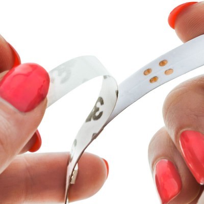 Mãos com unha vermelha segurando fita métrica branca flexível