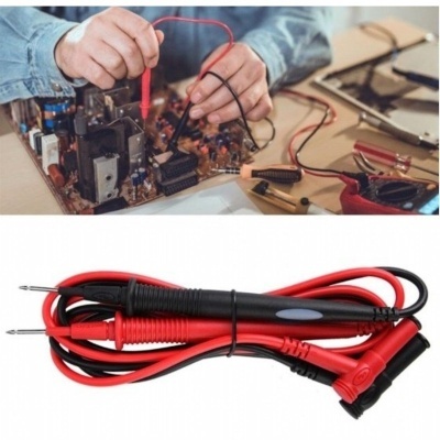 Multímetro com pistolas vermelhas e pretas e placa eletrónica com fios e componentes.