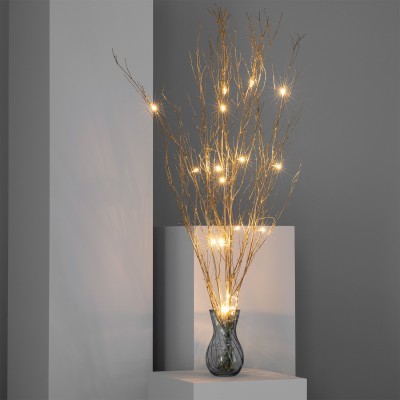 Arranjo decorativo com ramos dourados e luzes LED num vaso cinzento