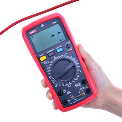 multímetro digital vermelho e preto na mão