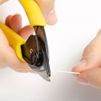 Alicate de corte com punhos amarelos a cortar fio branco