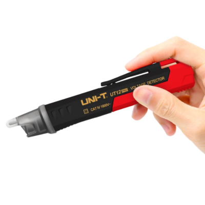 Detector de voltagem portátil preto e vermelho com texto dourado segurado por uma mão