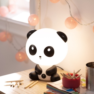 Lâmpada de mesa panda preta e branca em secretária com lápis e livros.