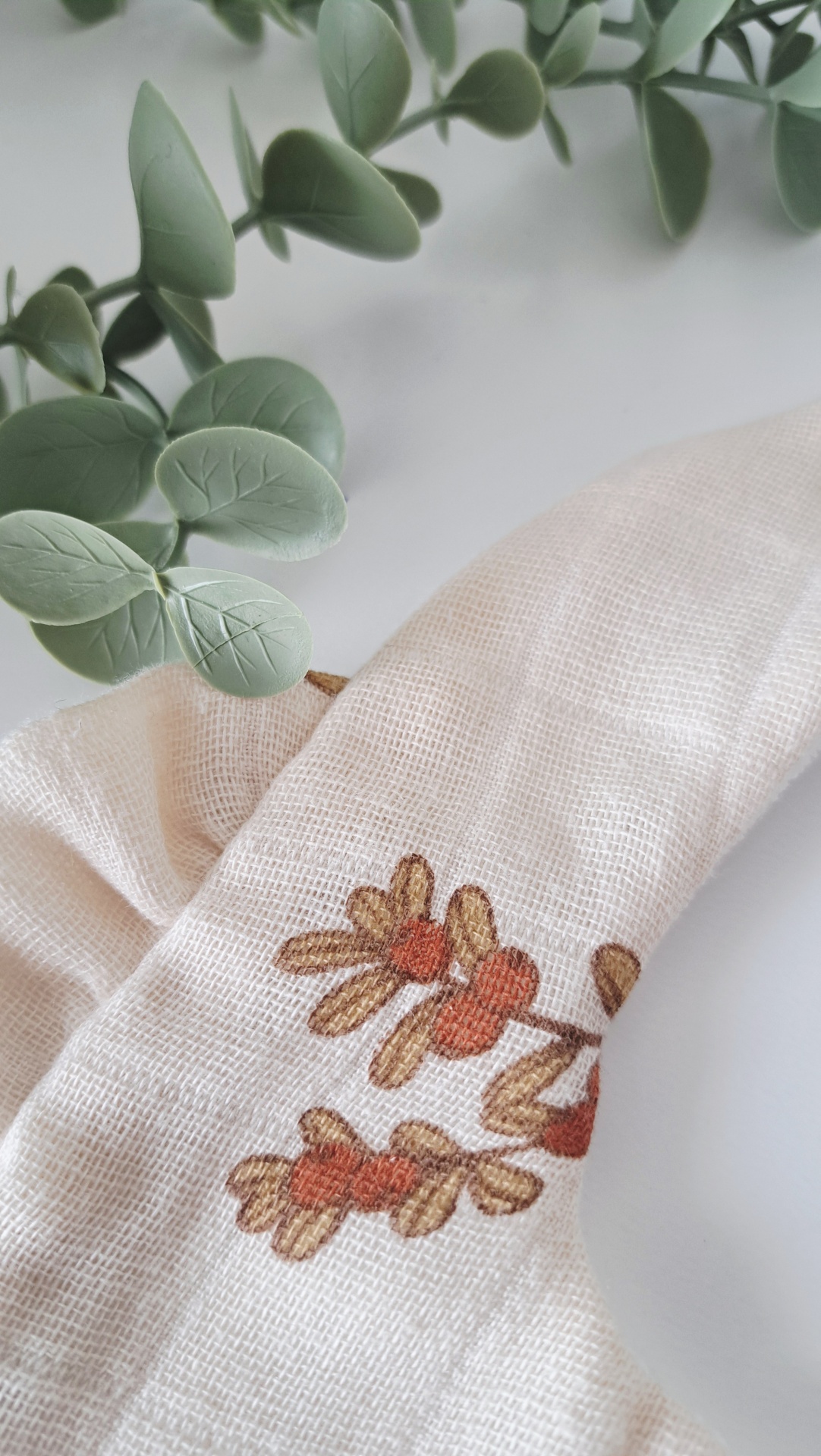 Babete ♥ terracota bouquet Pano de prato branco com padrão floral castanho e vermelho e tecido texturizado.