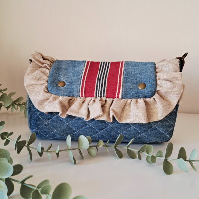 Bolsa de mão em tecido azul denim com folhos bege e detalhe vermelho com riscas
