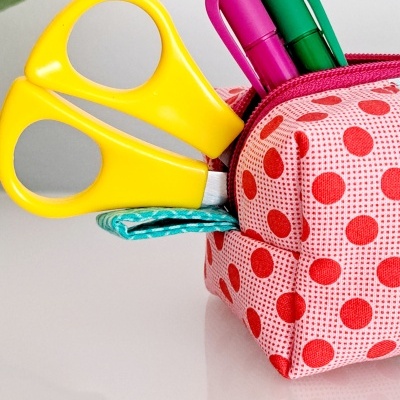Estojo tecido bolas vermelhas com canetas rosa e verde e tesoura amarela