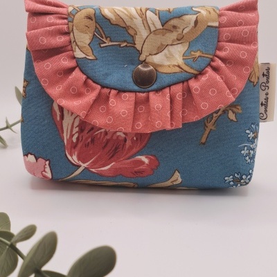 Carteira tecido azul com padrão floral e aba rosa plissada com botão metálico