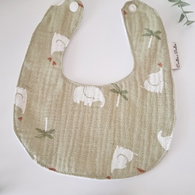 Babete bege com padrão de elefantes e palmeiras, com fecho de molas