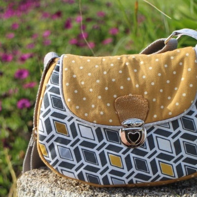 Bolsa pequena com padrão geométrico e aba amarela com bolinhas brancas