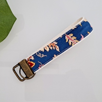 Chaveiro de tecido azul com padrão floral e fecho metálico bronze