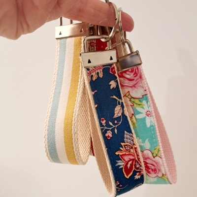 Três pulseiras de tecido com padrões coloridos penduradas em argolas metálicas