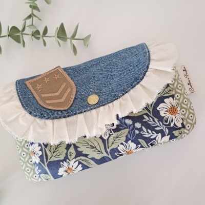 Bolsa floral com abas de ganga azul e folho branco em superfície branca