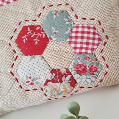 Mala patchwork hexagonal com costura vermelha e fecho metálico
