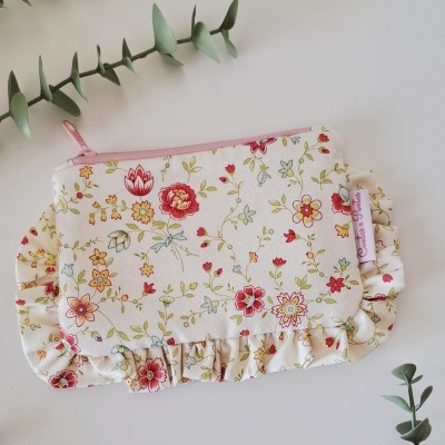 Porta-moedas floral com fecho quer-de-rosa e folhos, rodeado por ramos verdes