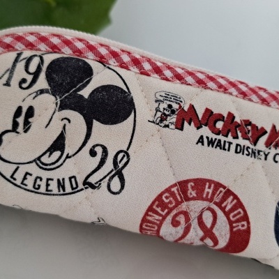 Estojo tecido com padrão de Mickey Mouse e texto em português.