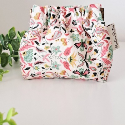 Bolsa pequena de tecido floral com etiqueta Creative Rocks sobre fundo branco com plantas verdes