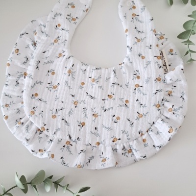 Babete redondo branco com padrão floral e volantes nas bordas
