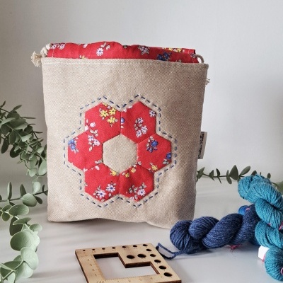 Bolsa de tecido bege com padrão floral vermelho e bordado azul.