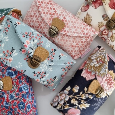 Seis carteiras pequenas em tecido com padrões florais e fecho metálico sobre superfície branca