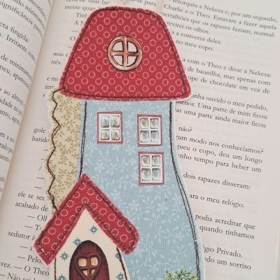 Marcador de livros em forma de casa colorida sobre livro aberto