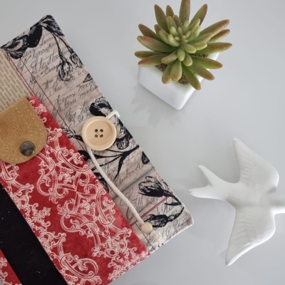 Capa patchwork para agenda com botão, vaso de planta e figura de pássaro sobre mesa branca