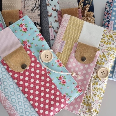 Carteiras coloridas em tecido com padrões florais, bolinhas e geométricos, com botões de madeira e detalhes em couro