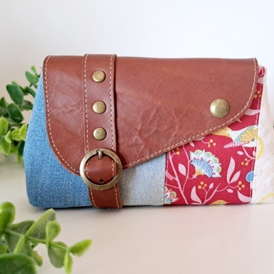 Carteira de tecido e couro com padrão floral e detalhes metálicos
