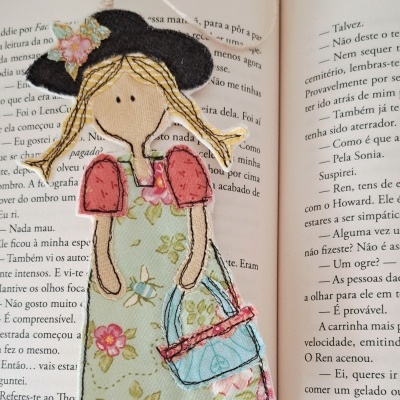 Marcador de livro de boneca em tecido colorido sobre livro aberto