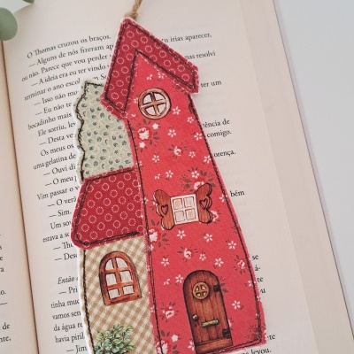 Marcador de livro em forma de casa colorida sobre livro aberto