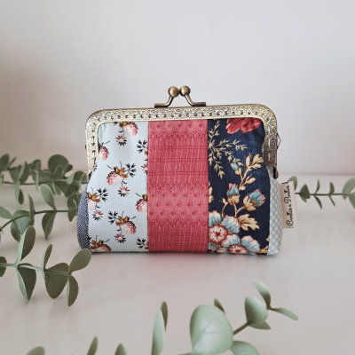 Carteira pequena de tecido patchwork com fecho metálico e três padrões florais, com etiqueta Costura e Pontos em fundo branco