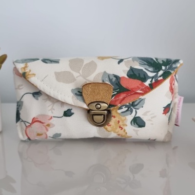 Bolsa de tecido floral com fecho metálico sobre mesa branca brilhante