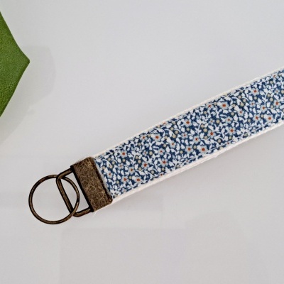 Chaveiro de tecido com padrão floral e argola metálica sobre superfície branca