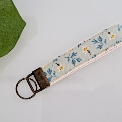 Chaveiro de tecido com padrão floral azul e amarelo e metal bronze