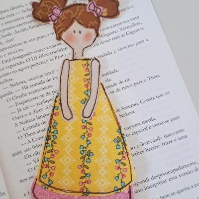 Marcador de página de tecido em forma de menina colorida sobre livro aberto