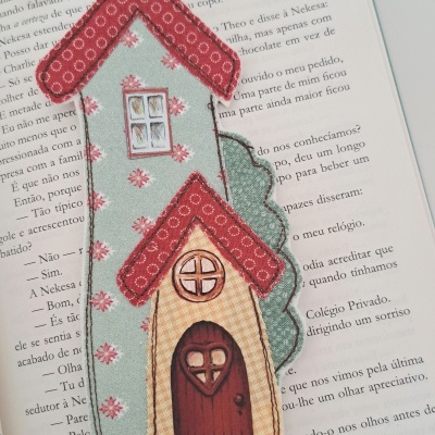 Marcador de páginas tecido em forma de casa colorida em livro aberto